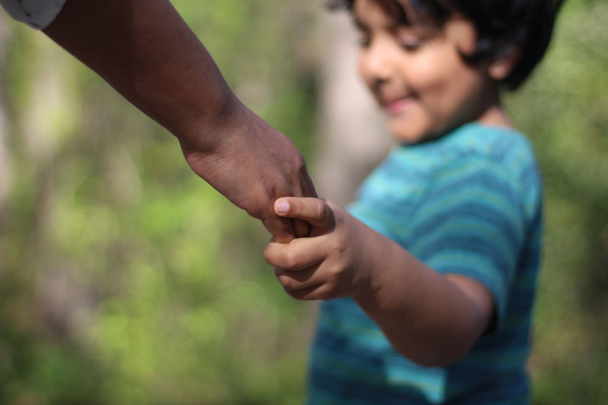 Carer holding kids hand